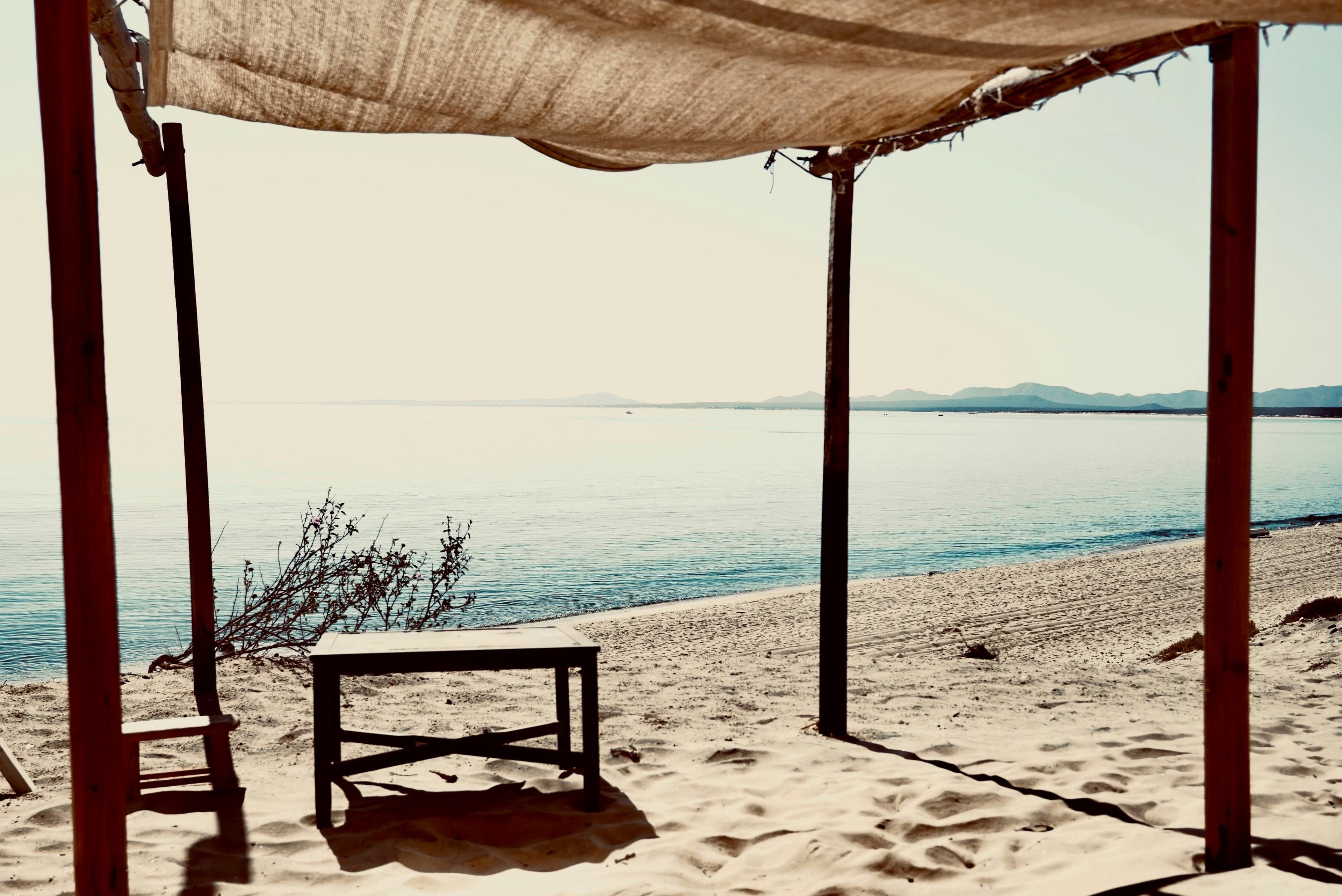 A shaded table on a quiet beach overlooking a calm sea